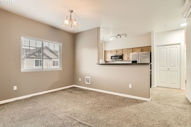 interior space featuring a chandelier, appliances with stainless steel finishes, light colored carpet, and dark countertops