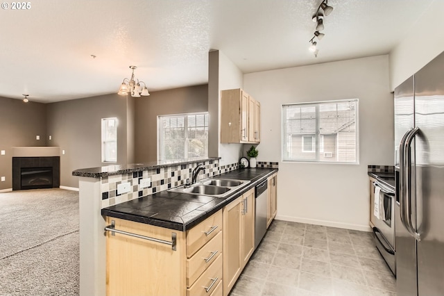 kitchen featuring a sink, appliances with stainless steel finishes, plenty of natural light, and dark countertops