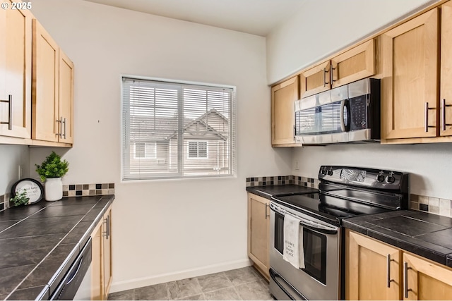 kitchen with stainless steel appliances, tile countertops, and light brown cabinets