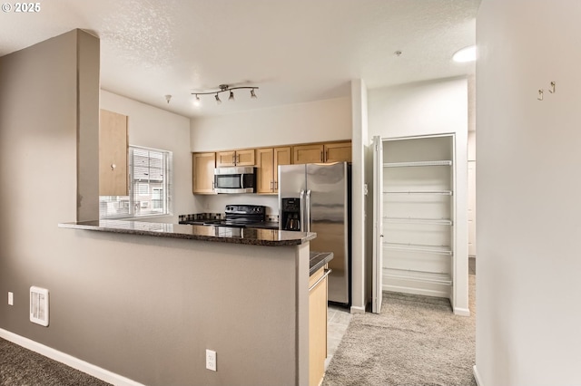 kitchen featuring dark stone countertops, baseboards, a peninsula, and stainless steel appliances