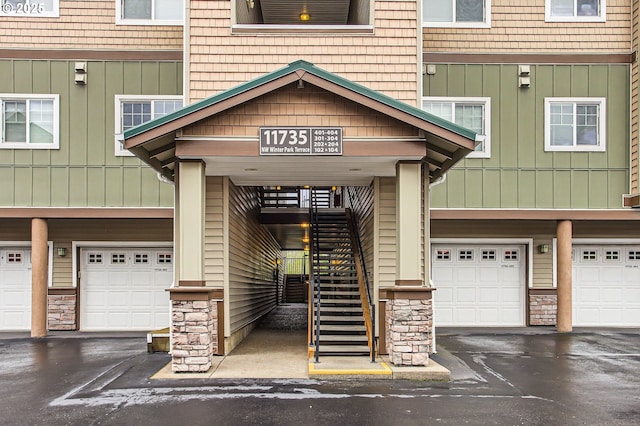 property entrance with driveway, stone siding, and a garage