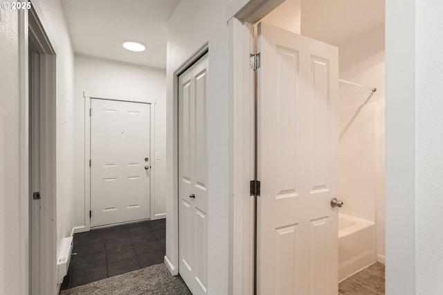 hall featuring baseboards and dark tile patterned flooring