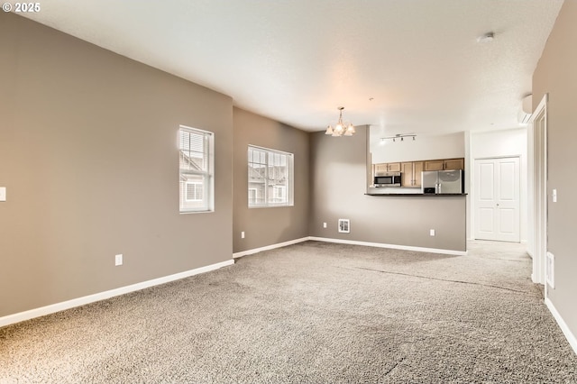 unfurnished living room featuring light carpet, baseboards, and a chandelier