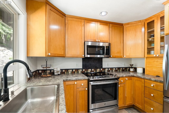 6750 SW Parkwest Ln, Portland, OR 97225 - kitchen featuring appliances with stainless steel finishes, a sink, glass insert cabinets, brown cabinetry, and dark countertops