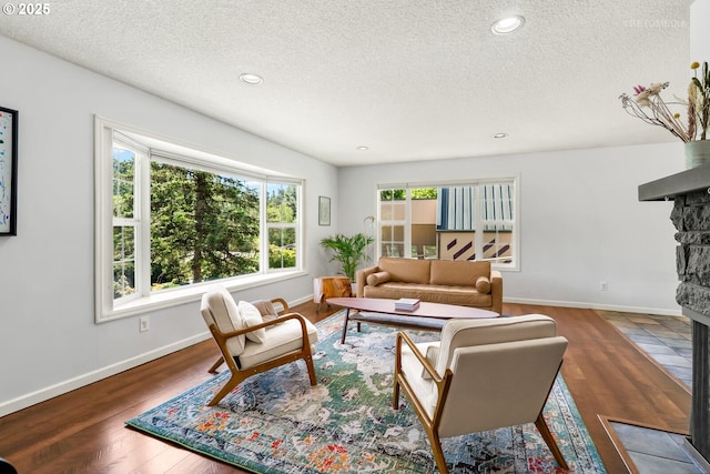6750 SW Parkwest Ln, Portland, OR 97225 - living area with a stone fireplace, a textured ceiling, wood finished floors, baseboards, and recessed lighting