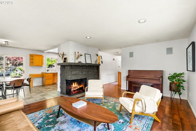 6750 SW Parkwest Ln, Portland, OR 97225 - living room featuring a stone fireplace, wood finished floors, recessed lighting, a textured ceiling, and baseboards