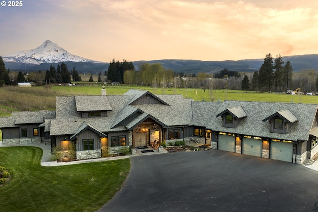 view of front of property with a mountain view, a chimney, a front lawn, and stone siding