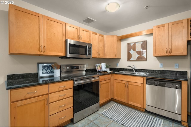 kitchen featuring dark stone countertops, sink, and appliances with stainless steel finishes