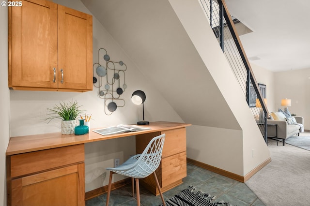 office space featuring light carpet, built in desk, and lofted ceiling