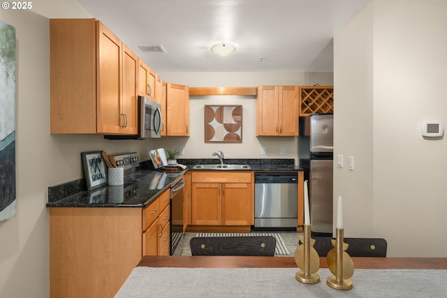 kitchen with sink, stainless steel appliances, and dark stone counters