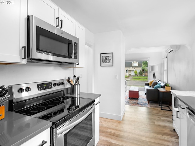 121 NE Edison St, Hillsboro, OR 97124 - kitchen with stainless steel appliances, a wall mounted AC, light wood-style flooring, and white cabinets