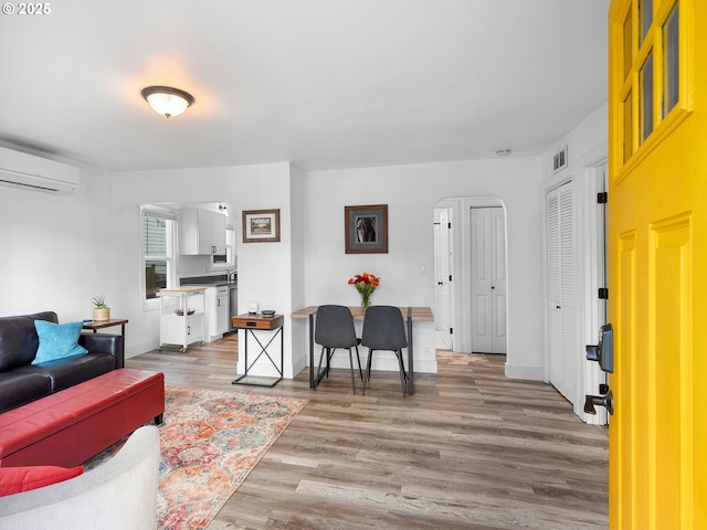 121 NE Edison St, Hillsboro, OR 97124 - living area with a wall mounted AC, arched walkways, light wood-style flooring, and baseboards