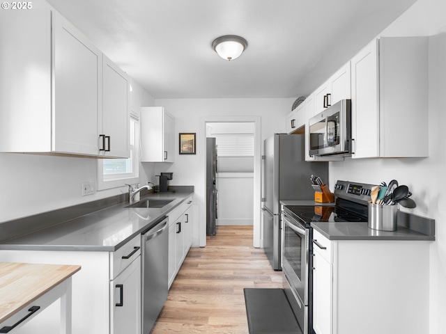 121 NE Edison St, Hillsboro, OR 97124 - kitchen featuring stainless steel appliances, a sink, light wood-style floors, and white cabinets