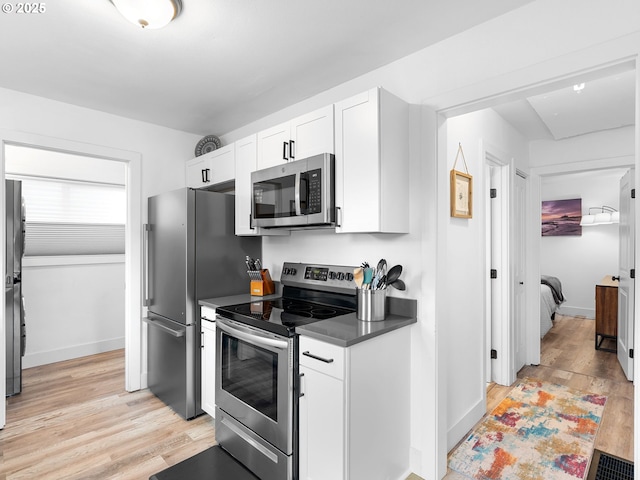 121 NE Edison St, Hillsboro, OR 97124 - kitchen featuring stainless steel appliances, light wood-style floors, white cabinets, and dark countertops
