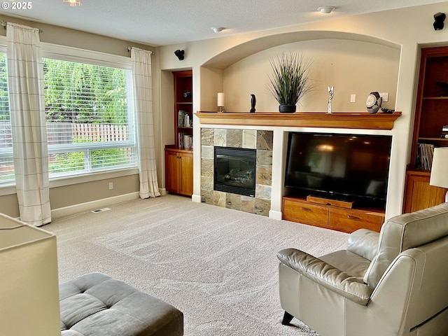 carpeted living room featuring baseboards, a tiled fireplace, and a textured ceiling