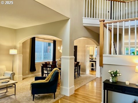 living area with arched walkways, wood finished floors, baseboards, and a high ceiling