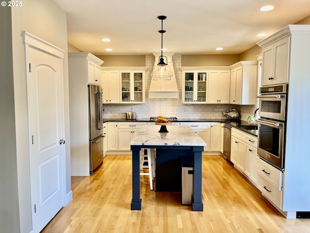 kitchen featuring stainless steel appliances, a kitchen island, decorative backsplash, light wood-style floors, and recessed lighting