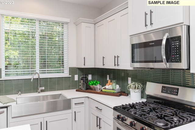 kitchen with tasteful backsplash, light countertops, appliances with stainless steel finishes, white cabinetry, and a sink