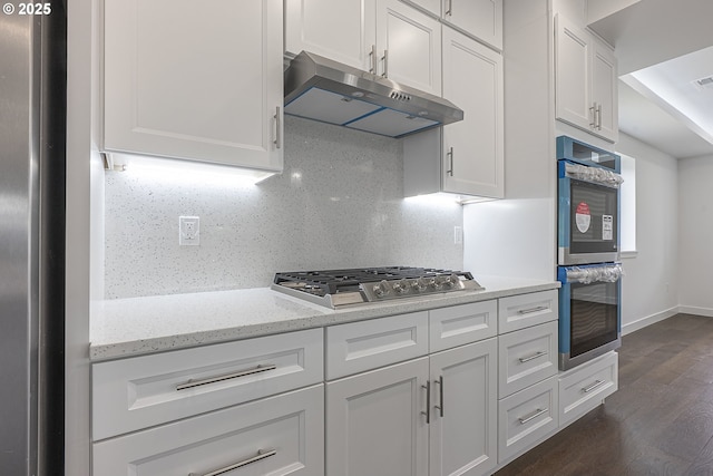 413 S Trade St, Amity, OR 97101 - kitchen with under cabinet range hood, stainless steel appliances, dark wood-type flooring, white cabinetry, and light stone counters