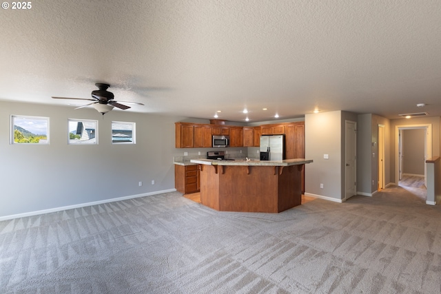 kitchen with stainless steel appliances, a kitchen bar, a textured ceiling, light countertops, and baseboards
