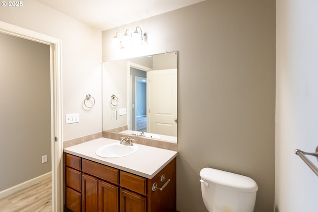 bathroom with wood finished floors, vanity, and toilet