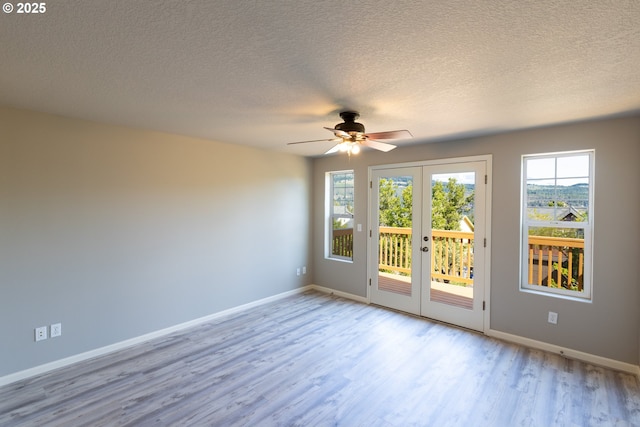 spare room featuring french doors, wood finished floors, baseboards, healthy amount of natural light, and a textured ceiling