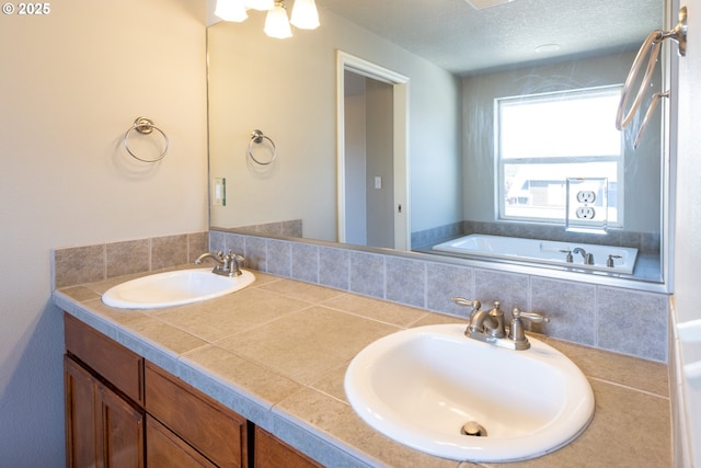 full bathroom with double vanity, a bathtub, and a textured ceiling
