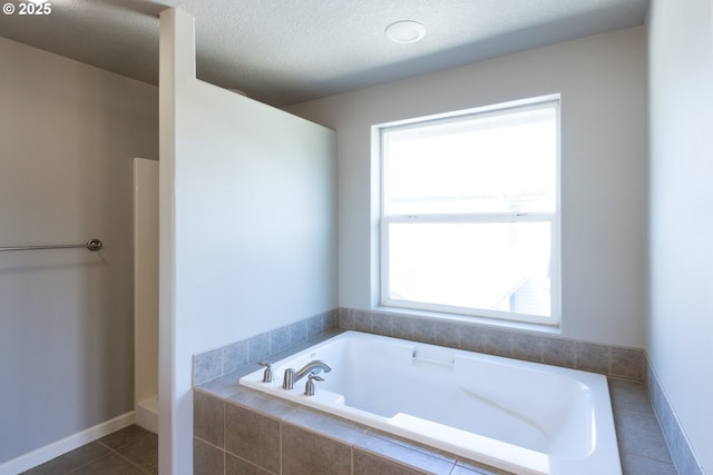 full bathroom featuring a garden tub, tile patterned floors, and a textured ceiling