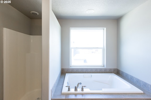 bathroom featuring a shower, a textured ceiling, and a bath