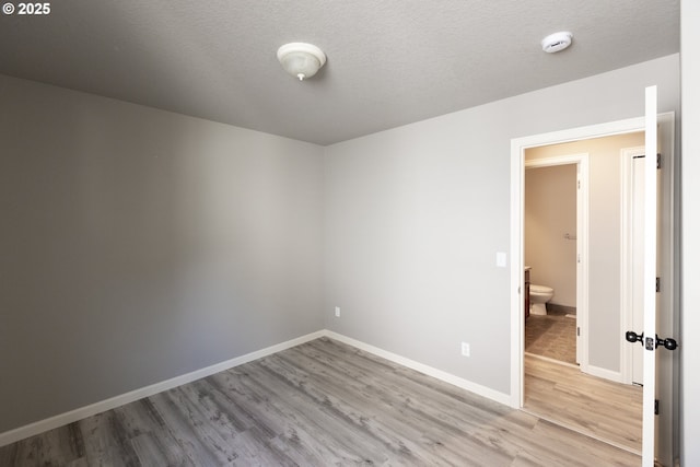unfurnished room featuring wood finished floors, a smoke detector, and baseboards