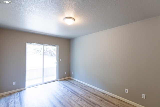 spare room featuring wood finished floors, a textured ceiling, and baseboards
