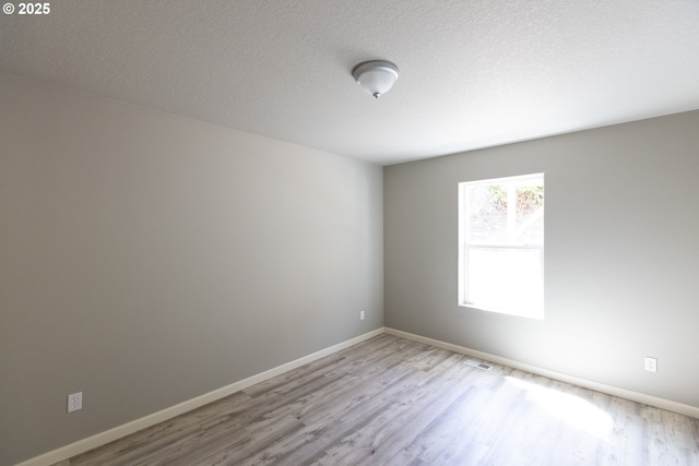 empty room with wood finished floors, baseboards, and a textured ceiling