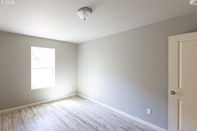 unfurnished room with light wood-style floors, baseboards, and a textured ceiling