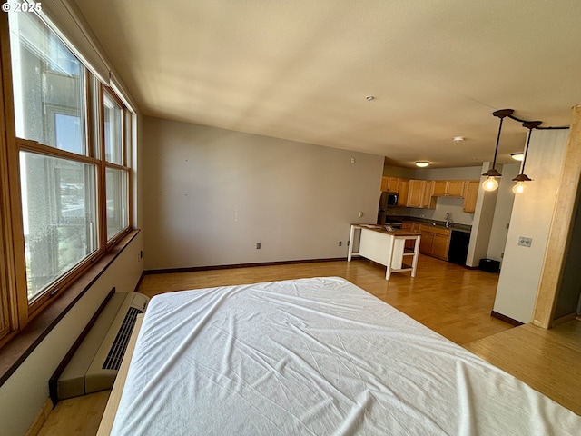 1134 SW Jefferson St Unit 503, Portland, OR 97201 - bedroom featuring baseboards, light wood-style floors, a wall unit AC, and a sink