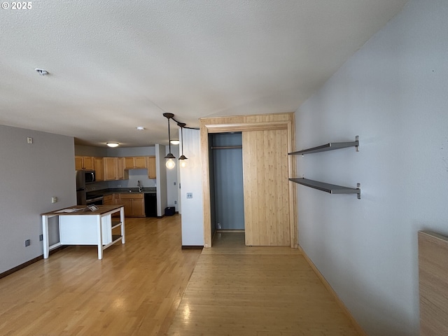 1134 SW Jefferson St Unit 503, Portland, OR 97201 - kitchen with dark countertops, light wood finished floors, a sink, baseboards, and dishwasher
