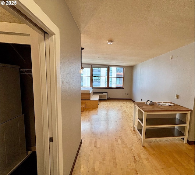 1134 SW Jefferson St Unit 503, Portland, OR 97201 - hall featuring light wood-type flooring, a textured ceiling, a wall mounted air conditioner, and baseboards