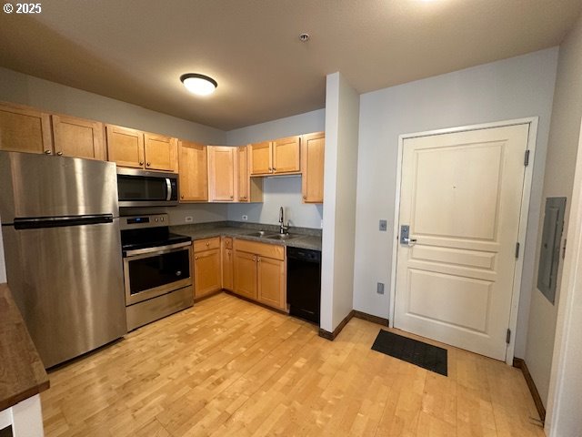 1134 SW Jefferson St Unit 503, Portland, OR 97201 - kitchen featuring stainless steel appliances, a sink, light wood-style flooring, light brown cabinets, and baseboards