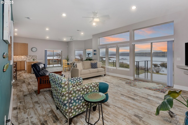 living room with light wood-type flooring, baseboards, a ceiling fan, and recessed lighting