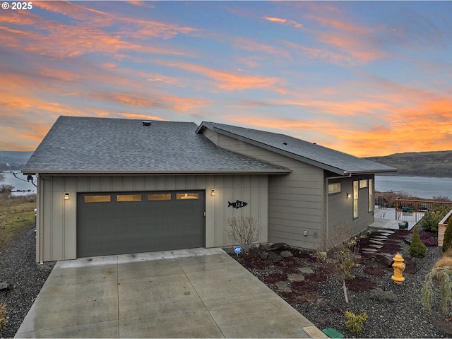 view of front of house with board and batten siding, an attached garage, driveway, and a shingled roof