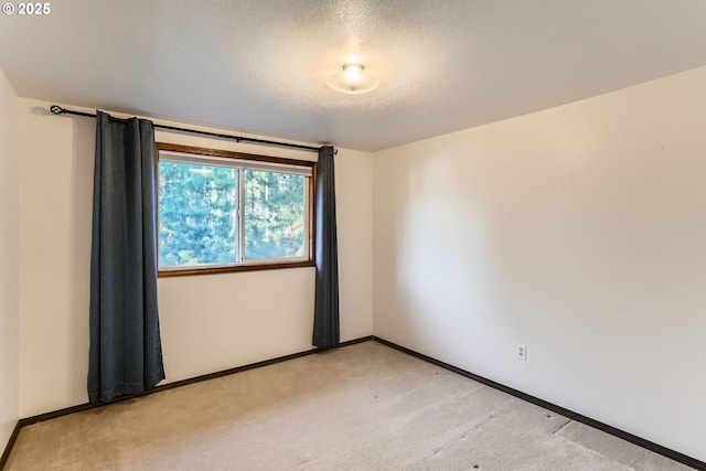 unfurnished room featuring baseboards, a textured ceiling, and light colored carpet