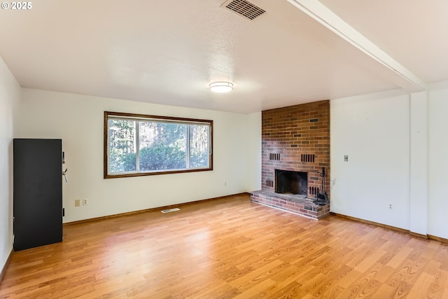 unfurnished living room with light wood-style floors, a brick fireplace, visible vents, and baseboards