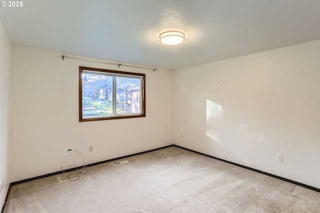 carpeted spare room with visible vents, a textured ceiling, and baseboards