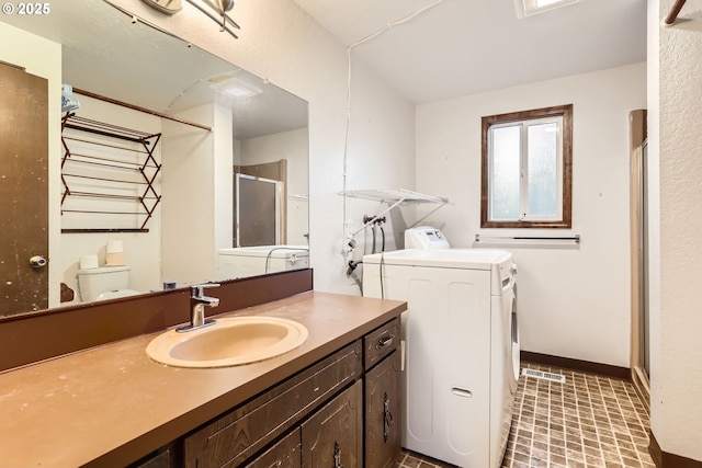 bathroom with baseboards, toilet, independent washer and dryer, vanity, and a shower stall