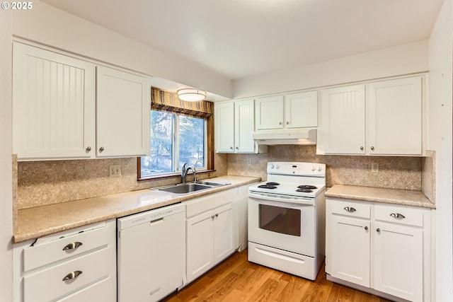 kitchen featuring under cabinet range hood, white appliances, a sink, white cabinetry, and decorative backsplash