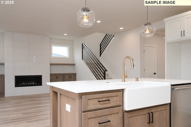 kitchen featuring pendant lighting, white cabinets, dishwasher, and a tile fireplace