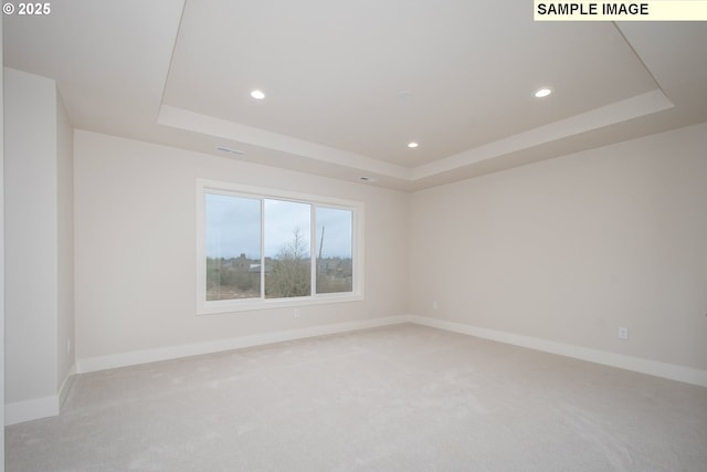 carpeted empty room with a tray ceiling