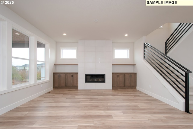 unfurnished living room with light hardwood / wood-style floors, a wealth of natural light, and a fireplace