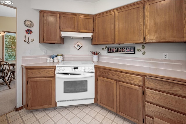 8911 SW 49th Ave, Portland, OR 97219 - kitchen with white range with electric stovetop, under cabinet range hood, light countertops, brown cabinets, and light flooring