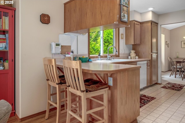 8911 SW 49th Ave, Portland, OR 97219 - kitchen with dishwasher, light countertops, a peninsula, brown cabinets, and a kitchen bar