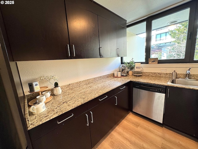 kitchen featuring light wood-style flooring, dishwasher, light countertops, and a sink